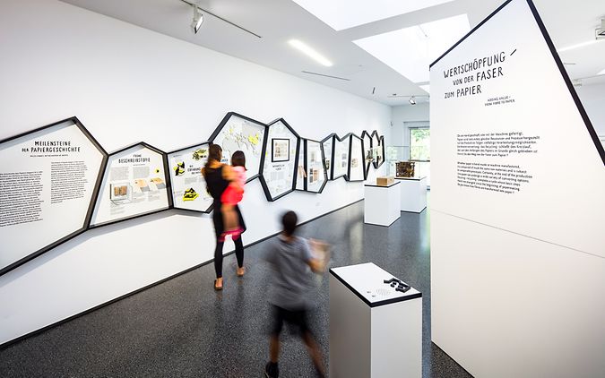 Frau und Kinder betrachten eine Ausstellung im Papiermuseum Düren.